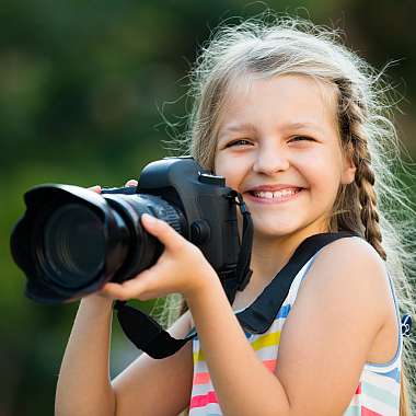 junges Mädchen fotografiert mit einer großen Kamera - elektronikversicherung - handyversicherung - iphone versicherung