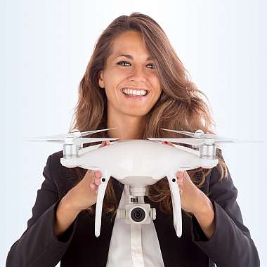 Junge Frau hält eine Quadrocopter-Drohne in beiden Händen